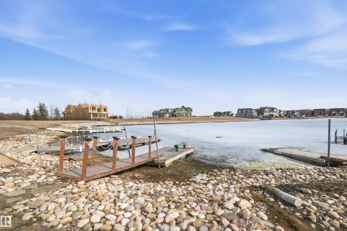 Waterfront property with several boat docks, a rocky shoreline, and views of the community across the water - 17 Sunset Harbour, Rural Wetaskiwin County, AB - Outdoor With Body Of Water With View