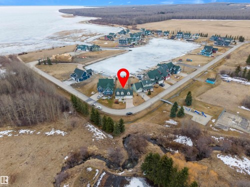 Aerial view of the property and surrounding community, featuring waterfront access and nearby recreational amenities including a playground and sports court - 17 Sunset Harbour, Rural Wetaskiwin County, AB - Outdoor With Body Of Water With View
