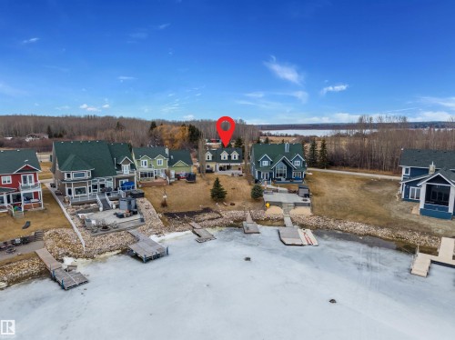 Aerial view of the property with a lakefront location, featuring a two-story home with a light-colored exterior and a dark roof - 17 Sunset Harbour, Rural Wetaskiwin County, AB - Outdoor With View