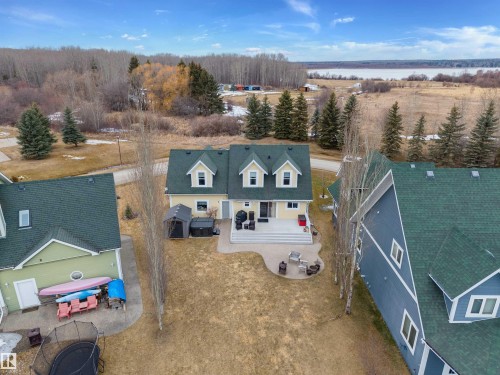 The property features a spacious rear patio area, with a multi-level design and a defined section for outdoor seating - 17 Sunset Harbour, Rural Wetaskiwin County, AB - Outdoor With View