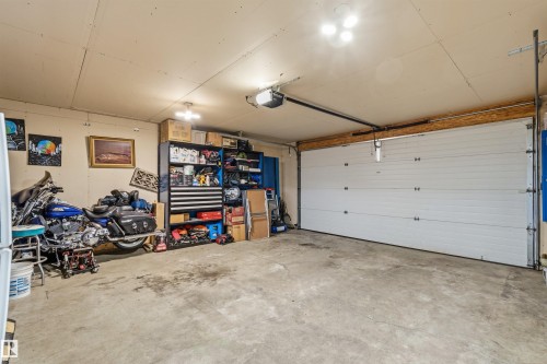The property includes a spacious garage with a large white garage door and a concrete floor - 17 Sunset Harbour, Rural Wetaskiwin County, AB - Indoor Photo Showing Garage