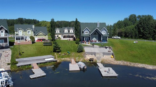 The property features a waterfront location with a private dock - 17 Sunset Harbour, Rural Wetaskiwin County, AB - Outdoor With Body Of Water With Deck Patio Veranda