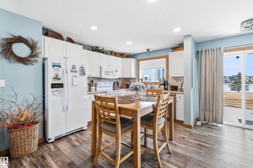 The kitchen features white cabinetry, a white refrigerator, and a sliding glass door leading to the outdoors - 17 Sunset Harbour, Rural Wetaskiwin County, AB - Indoor