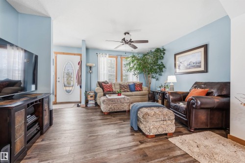 Spacious living area featuring light blue walls, wood-look flooring, and a ceiling fan - 17 Sunset Harbour, Rural Wetaskiwin County, AB - Indoor Photo Showing Living Room