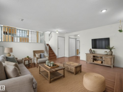 This living area features light-colored walls and wood flooring, complemented by a light-colored area rug - 14523 32 Street, Edmonton, AB - Indoor Photo Showing Living Room