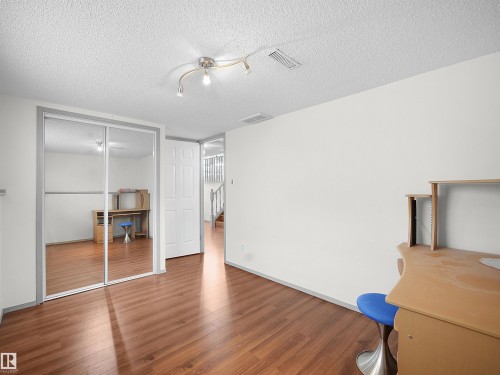 This interior space features hardwood flooring, white walls, and a ceiling-mounted light fixture - 14523 32 Street, Edmonton, AB - Indoor Photo Showing Other Room