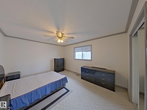 The room features a neutral color palette, a window with blinds, and a ceiling fan with integrated lighting - 14523 32 Street, Edmonton, AB - Indoor Photo Showing Bedroom
