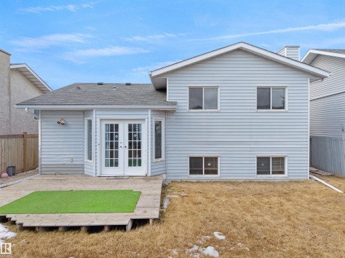 The property features light blue siding, a wooden deck with a green mat, and a brown yard - 14523 32 Street, Edmonton, AB - Outdoor With Exterior