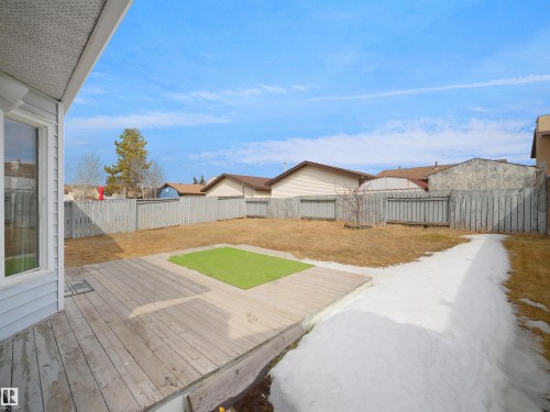 The property features a spacious backyard with a wooden deck, a light-colored privacy fence, and a grassy area - 14523 32 Street, Edmonton, AB - Outdoor