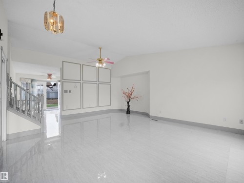 Spacious living area featuring polished tile flooring, a decorative wall panel, and a ceiling fan - 14523 32 Street, Edmonton, AB - Indoor Photo Showing Other Room