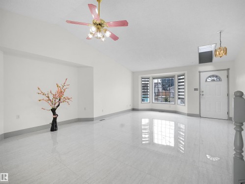 The property features high ceilings with a decorative ceiling fan, large bay windows providing natural light, and sleek tile flooring throughout - 14523 32 Street, Edmonton, AB - Indoor Photo Showing Other Room