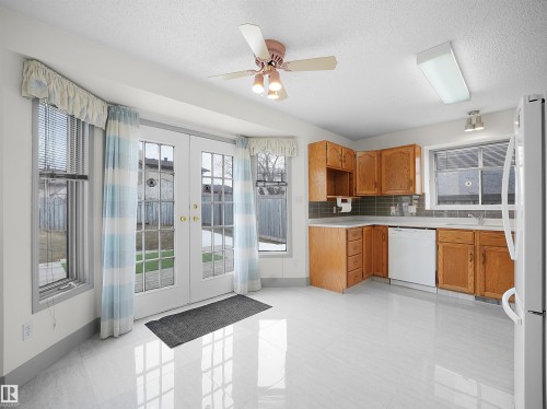 The kitchen features wood cabinetry, a white dishwasher, and a white refrigerator - 14523 32 Street, Edmonton, AB - Indoor Photo Showing Kitchen