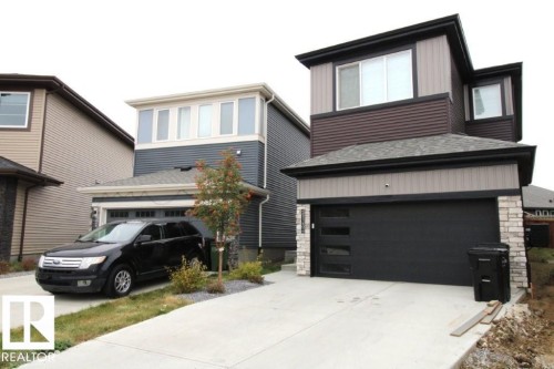 The property features a concrete driveway and an attached garage with a modern black door and stone accents - 22140 81 Avenue, Edmonton, AB 