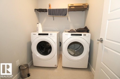 Dedicated laundry area featuring a white front-loading washer and dryer, light-colored walls, and shelving - 22140 81 Avenue, Edmonton, AB 