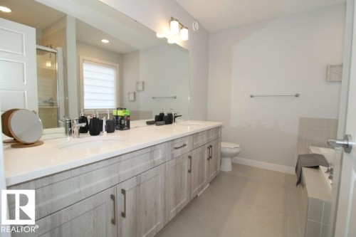 The bathroom features a double vanity with two sinks, light-toned cabinetry, and a large mirror - 22140 81 Avenue, Edmonton, AB 
