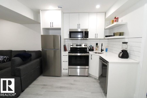 This kitchen features white cabinetry, stainless steel appliances, a white subway tile backsplash, and light-colored flooring - 22140 81 Avenue, Edmonton, AB 