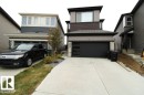 The property features a concrete driveway and a modern black garage door with frosted window panels - 22140 81 Avenue, Edmonton, AB 