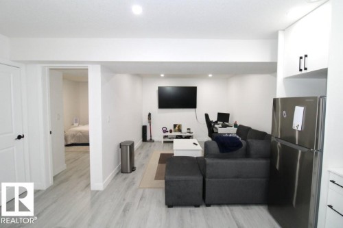 Living area with light-toned flooring, recessed lighting, and a stainless steel refrigerator - 22140 81 Avenue, Edmonton, AB 