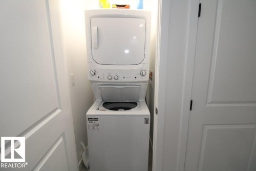 Compact laundry area featuring a white stacked washer and dryer unit - 22140 81 Avenue, Edmonton, AB 