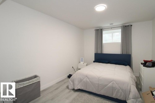 Bedroom featuring light-colored walls, light-toned flooring, and a window with blinds and drapes - 22140 81 Avenue, Edmonton, AB 