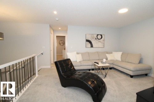 This inviting living space features light grey carpeting, recessed lighting, and a white railing with dark vertical balusters - 22140 81 Avenue, Edmonton, AB 