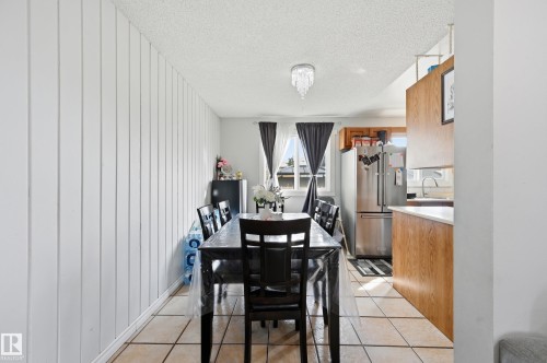 Dining area featuring tiled flooring, a light fixture, and a window with dark curtains - 9031 133 Avenue, Edmonton, AB - Indoor Photo Showing Dining Room