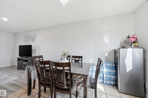 This dining area features tile flooring, a white panel accent wall, and a dining table with chairs - 9031 133 Avenue, Edmonton, AB - Indoor Photo Showing Dining Room