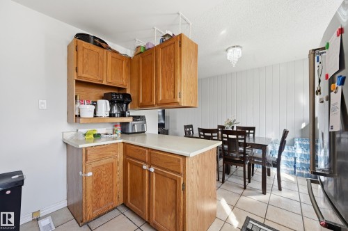 The kitchen features wood cabinetry and light-colored countertops - 9031 133 Avenue, Edmonton, AB - Indoor Photo Showing Kitchen