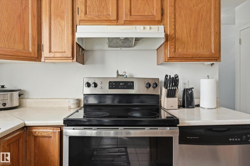 The kitchen features wood cabinetry, a stainless steel range with a black cooktop, and light-colored countertops - 9031 133 Avenue, Edmonton, AB - Indoor Photo Showing Kitchen