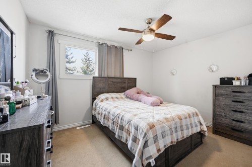 This room features a window with natural light, a ceiling fan with integrated lighting, and carpeted flooring - 9031 133 Avenue, Edmonton, AB - Indoor Photo Showing Bedroom