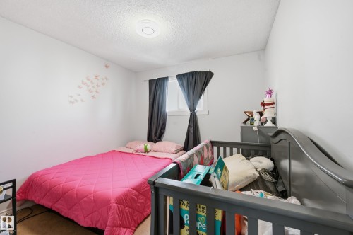 This room features a window with dark curtains, light-colored walls, and a ceiling light fixture - 9031 133 Avenue, Edmonton, AB - Indoor Photo Showing Bedroom