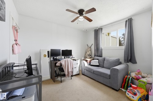 This room features a ceiling fan, a window with grey curtains, and light-colored carpeting - 9031 133 Avenue, Edmonton, AB - Indoor