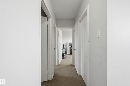 This property features a hallway with light-colored carpet, white walls, and white doors, providing a neutral aesthetic - 9031 133 Avenue, Edmonton, AB - Indoor Photo Showing Other Room