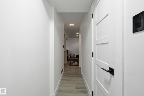 Hallway with light-toned flooring, recessed lighting, and a white door featuring a contemporary black handle - 9031 133 Avenue, Edmonton, AB - Indoor Photo Showing Other Room