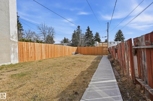 The property features a yard with a concrete pathway and a newly installed wooden fence - 9031 133 Avenue, Edmonton, AB - Outdoor
