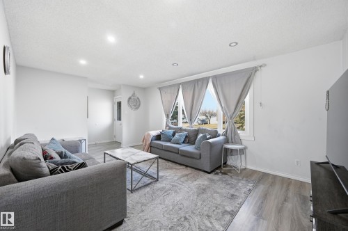 The living area features light-colored flooring, recessed lighting, and large windows that provide views of the outdoors - 9031 133 Avenue, Edmonton, AB - Indoor Photo Showing Living Room