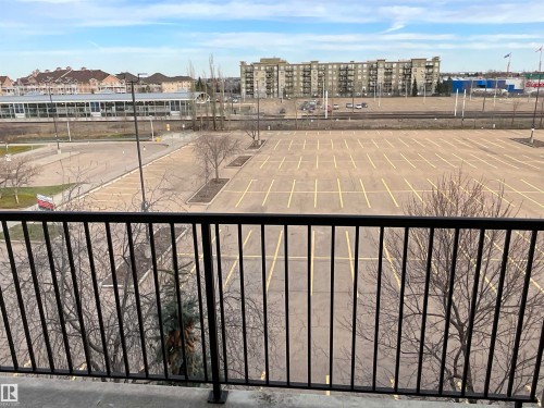 Balcony with black metal railing overlooking a large paved parking area - 408 309 Clareview Station Drive Nw, Edmonton, AB - Outdoor With View