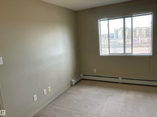 Spacious room featuring a large window, light-colored walls, and baseboard heating - 408 309 Clareview Station Drive Nw, Edmonton, AB - Indoor Photo Showing Other Room