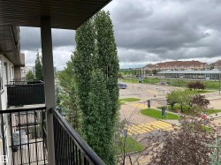 Private balcony with black metal railings, offering an elevated perspective of the surrounding streetscape and distant commercial structures - 