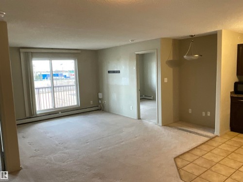 Living area featuring sliding glass patio doors, neutral carpeting, and a semi-flush mount light fixture - 408 309 Clareview Station Drive Nw, Edmonton, AB - Indoor Photo Showing Other Room