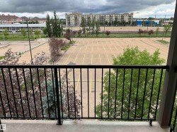 Balcony with a black metal railing overlooking an expansive paved parking area - 