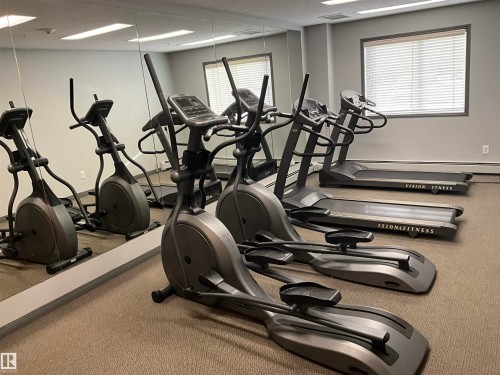 Dedicated fitness area featuring extensive mirrored walls, recessed lighting, wall-to-wall carpeting, and multiple cardio machines - 408 309 Clareview Station Drive Nw, Edmonton, AB - Indoor Photo Showing Gym Room