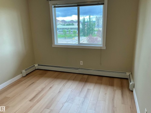 Light-colored wood-finish flooring, neutral wall paint, and a large window with blinds - 408 309 Clareview Station Drive Nw, Edmonton, AB 