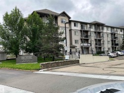 Multi-story residential building featuring private balconies, individual windows, exterior lighting, and a paved parking area - 