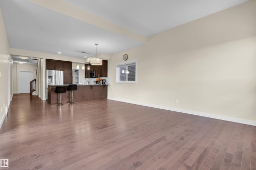Expansive living area featuring hardwood flooring, light-colored walls, and a window for natural light - 3071 Carpenter Landing Landing, Edmonton, AB - Indoor