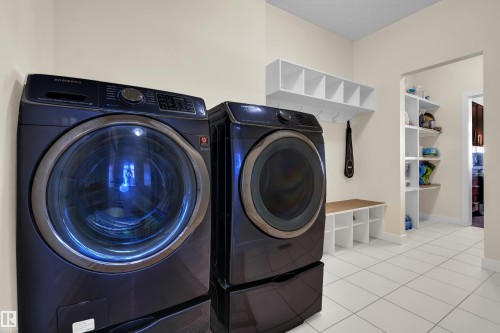 Laundry area featuring white tiled flooring, a built-in bench with storage cubbies, and overhead shelving with hooks - 3071 Carpenter Landing Landing, Edmonton, AB - Indoor Photo Showing Laundry Room