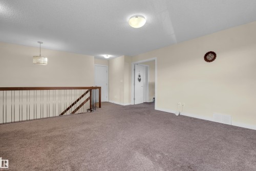 The property features a staircase with a wooden handrail and metal balusters - 3071 Carpenter Landing Landing, Edmonton, AB - Indoor Photo Showing Other Room