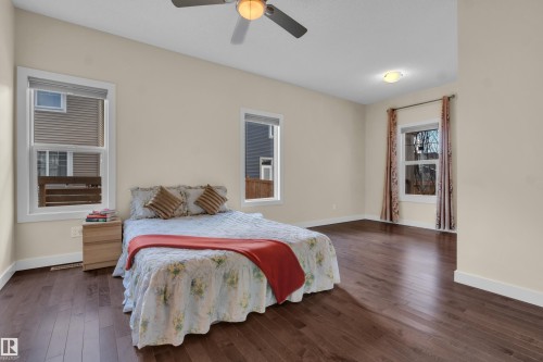 This spacious room features rich hardwood flooring, light-colored walls, and two windows providing natural light - 3071 Carpenter Landing Landing, Edmonton, AB - Indoor Photo Showing Bedroom