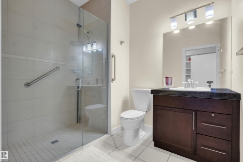 The bathroom features a glass-enclosed shower with white tiled walls and floor, a toilet, and a vanity with a dark countertop and white sink - 3071 Carpenter Landing Landing, Edmonton, AB - Indoor Photo Showing Bathroom