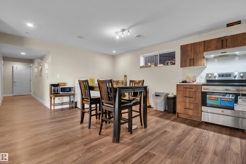 This open-concept living area features hardwood style flooring, recessed lighting, and a kitchen with wood cabinetry and stainless steel appliances - 3071 Carpenter Landing Landing, Edmonton, AB - Indoor